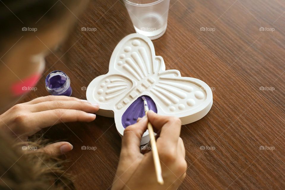 Girl’s hands panting a gypsum butterfly. Art workshop 