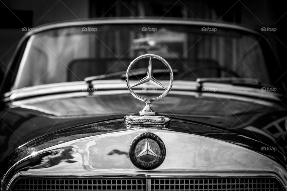 A portrait of the Mercedes benz emblem on the hood of an oldtimer Mercedes benz car.