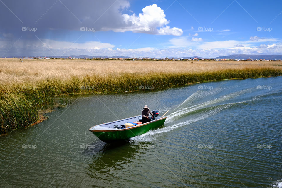 Boat sailing at speed over lake titicaca during the day with blue skies