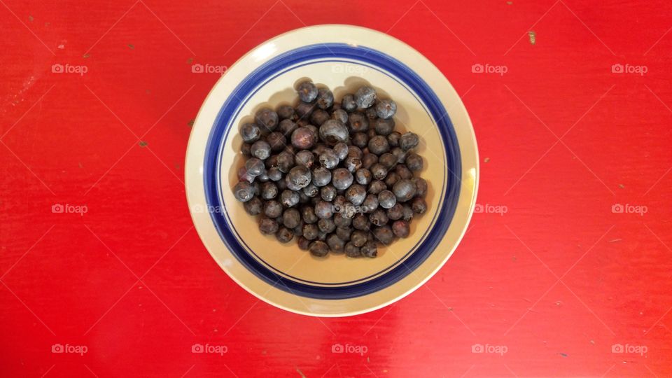 Blueberries in bowl with blue accent outline on red table