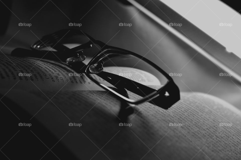 black and white photo. glasses on the book