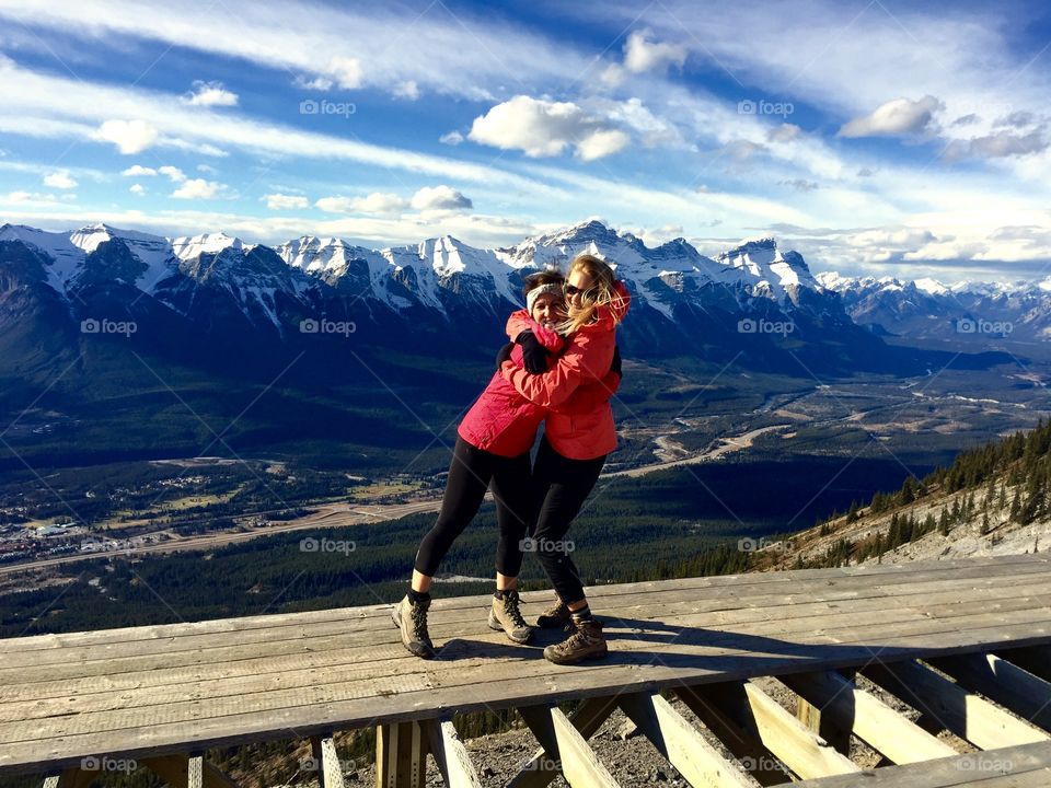 Mother and daughter hugging in front of snowing mountain