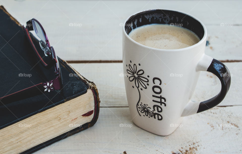 Coffee, book and glasses on desktop.