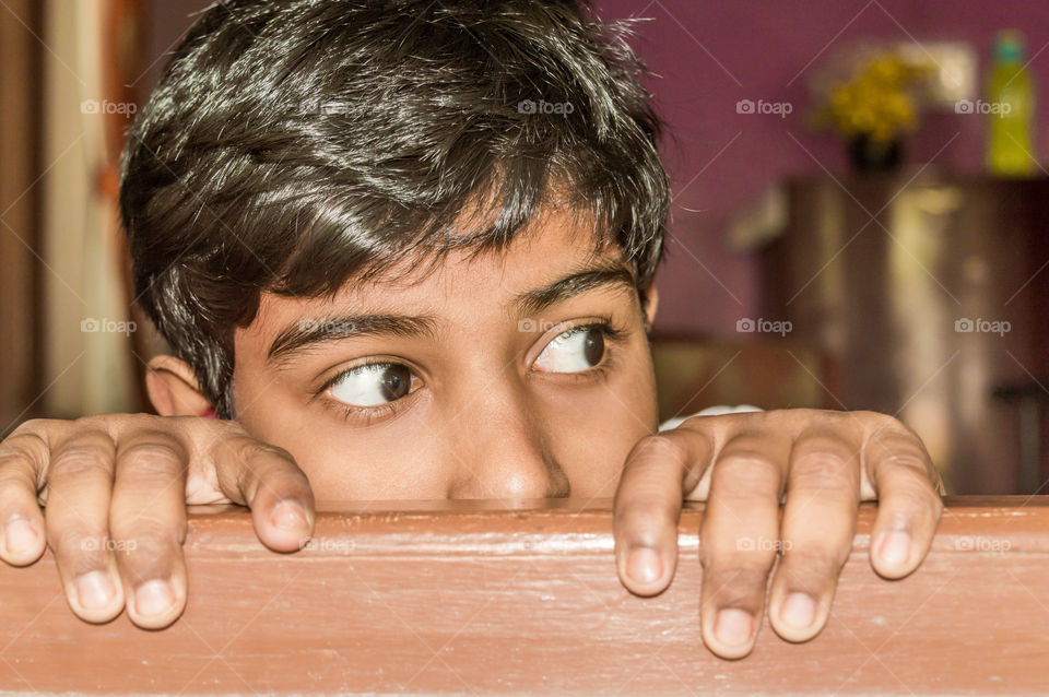 Young boy curiously looking outside through a window.