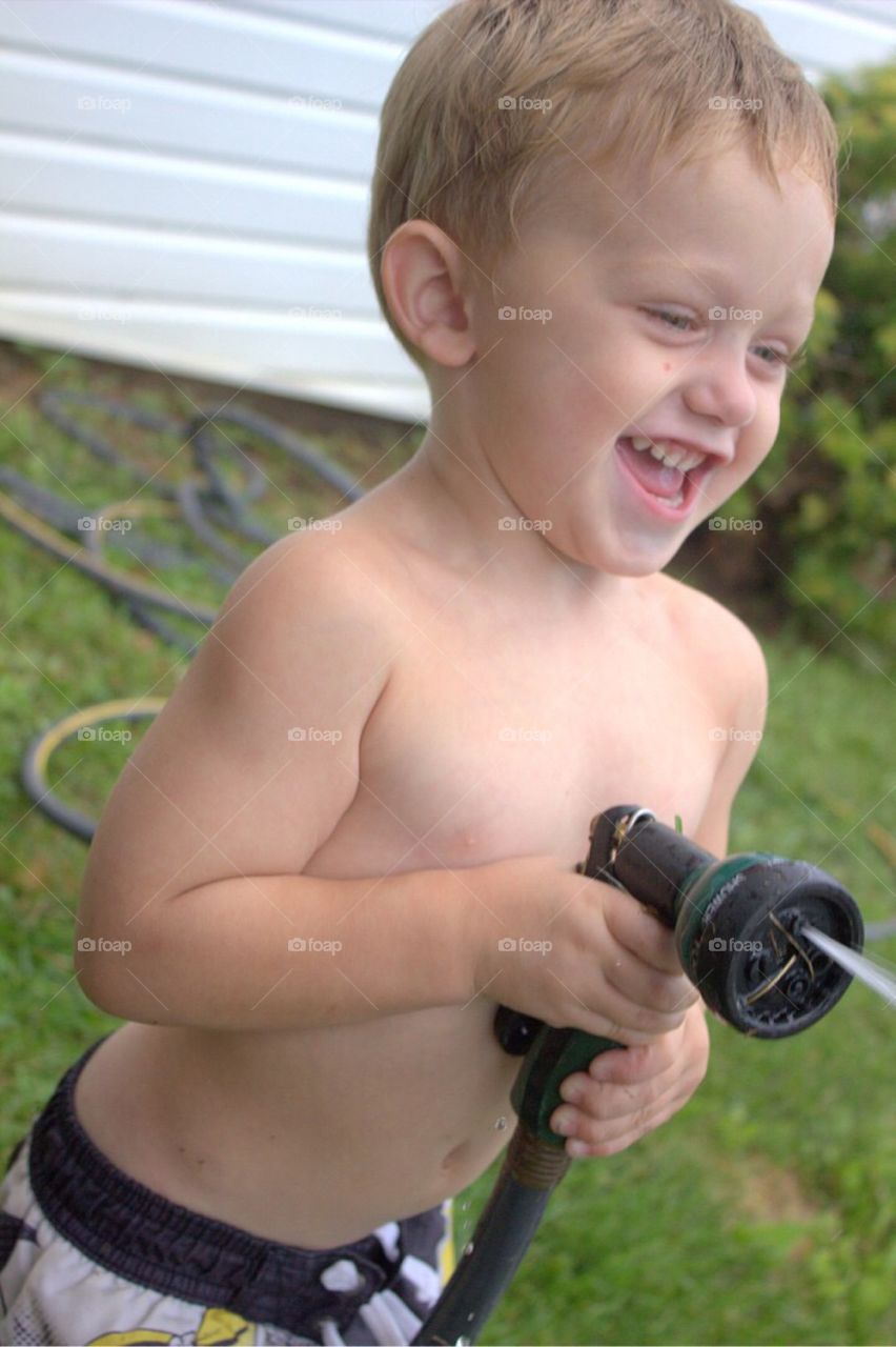 Portrait of a boy playing with hose in garden