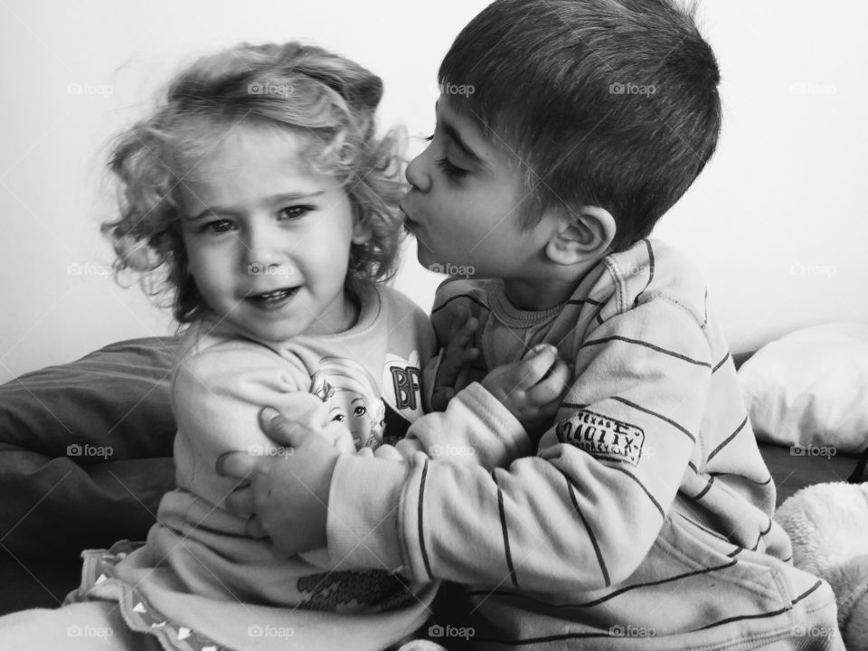 Little brother and sister sitting on bed