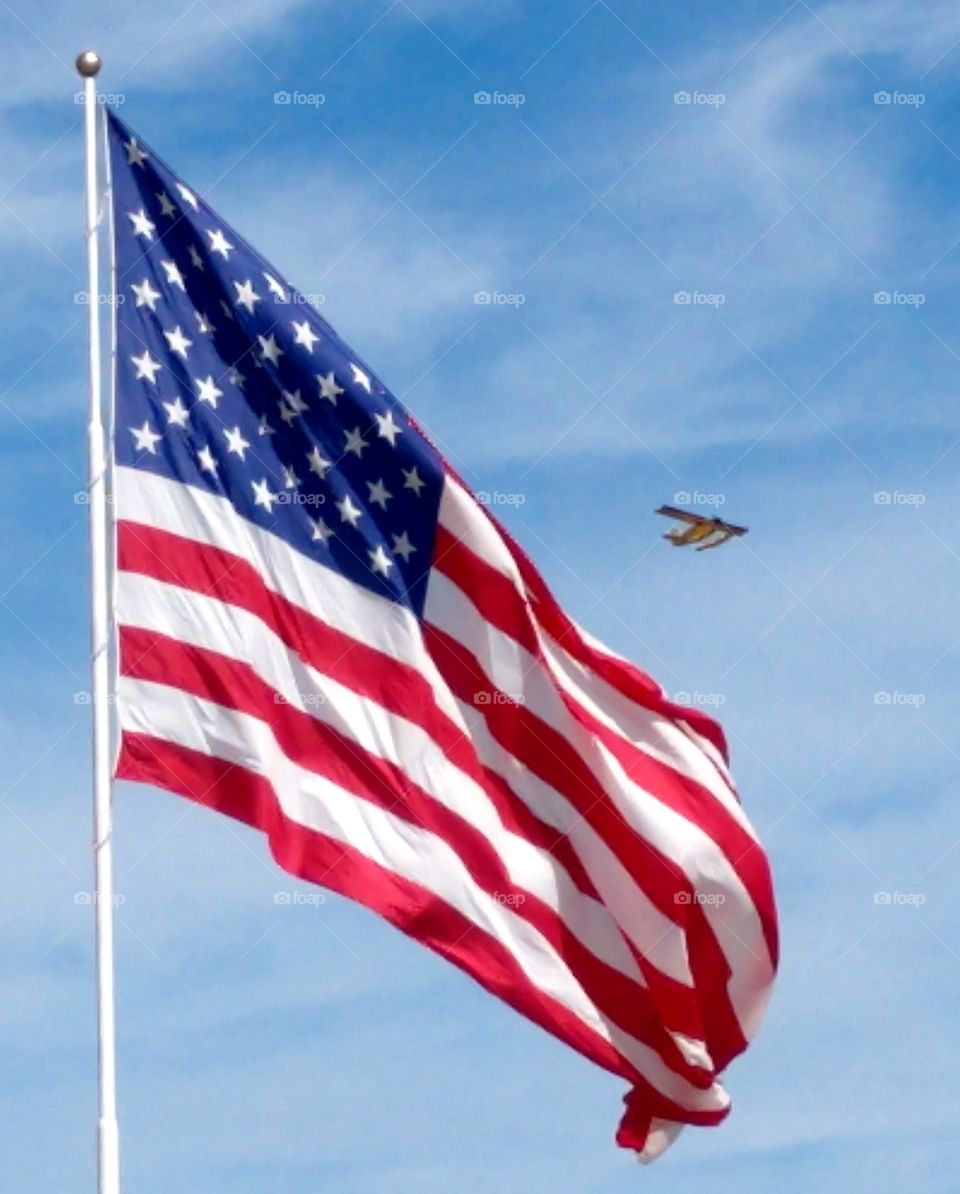 Flag flying with plane flying in sky