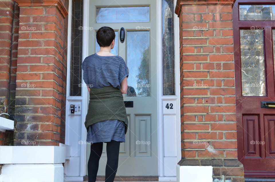 Female canvasser knocking on a green door and standing outside