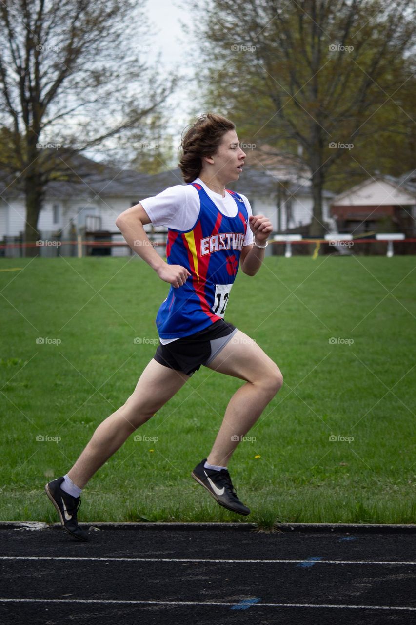 Teenager running on field track in a race