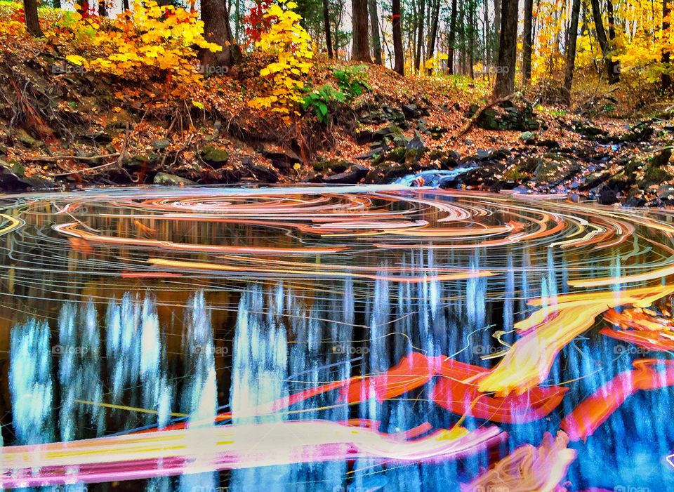 A long exposure of leaves swirling around a woodland stream. 