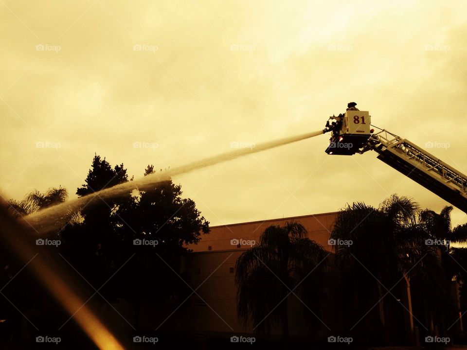Firemen on a ladder using hose