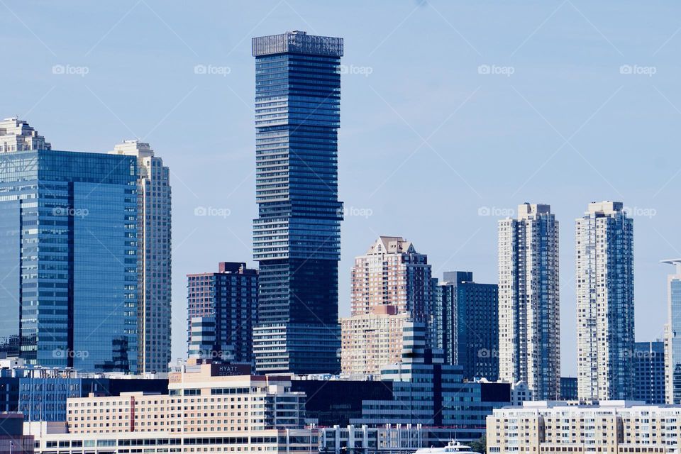 A skyscraper shaped like stacks of giant CD cases, soars in the sky. 