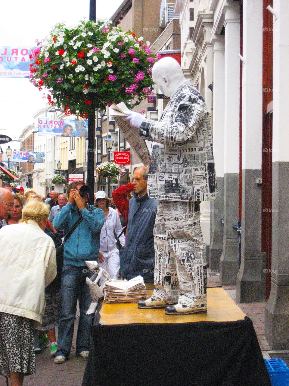 Living statue man standing in newspaper clothes 