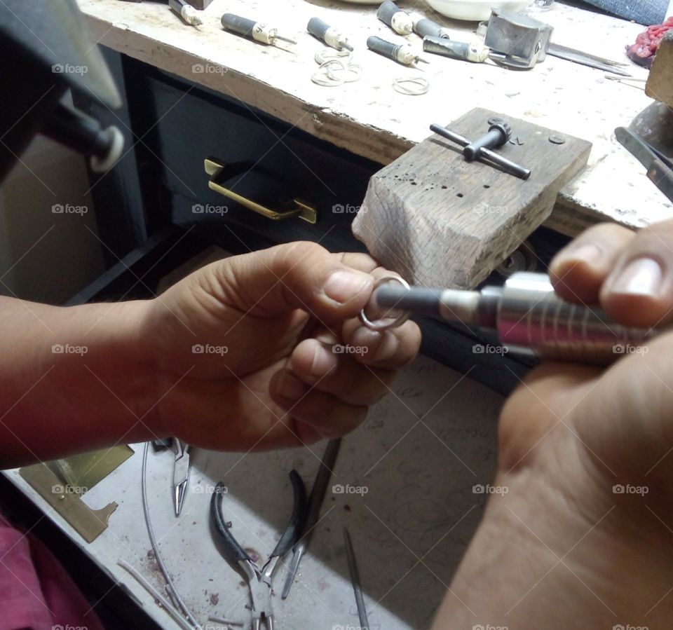 limpiando un anillo en plata antes de ser terminado. para joyería. en un taller en el centro de la ciudd