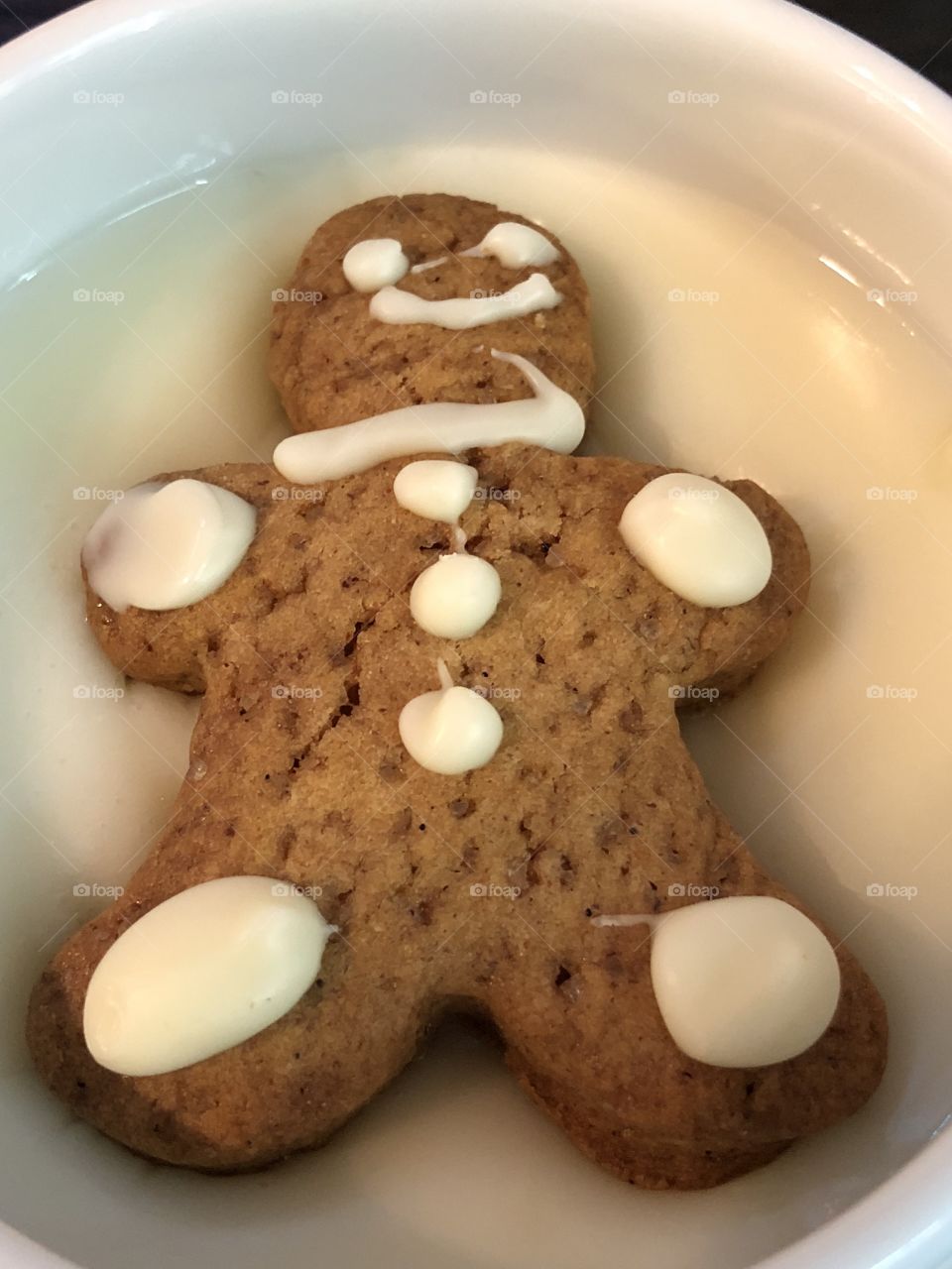 Gingerbread cookie sinking in a cup of white chocolate