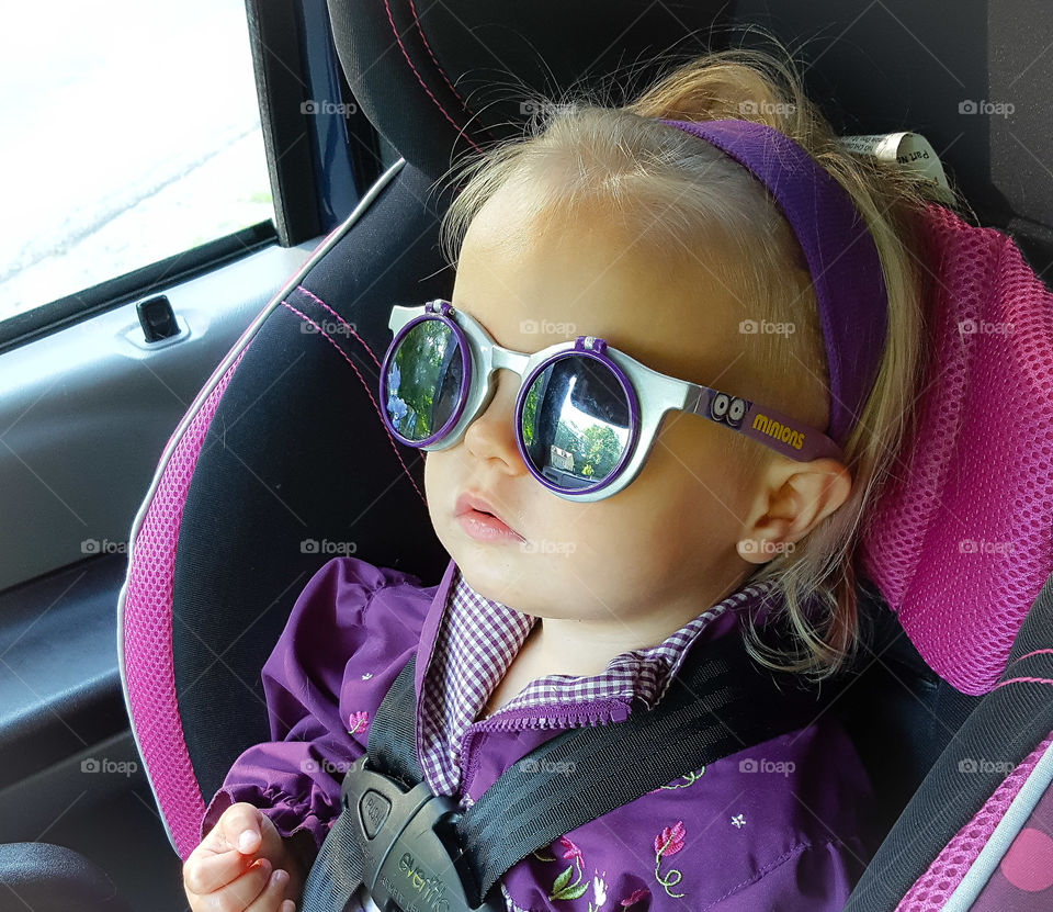 Cute girl wearing sunglasses sitting in car