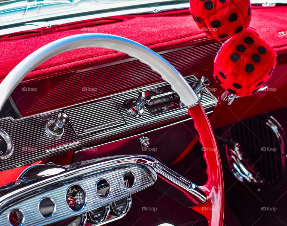 Classic car steering wheel, dash and fuzzy dice in bright red