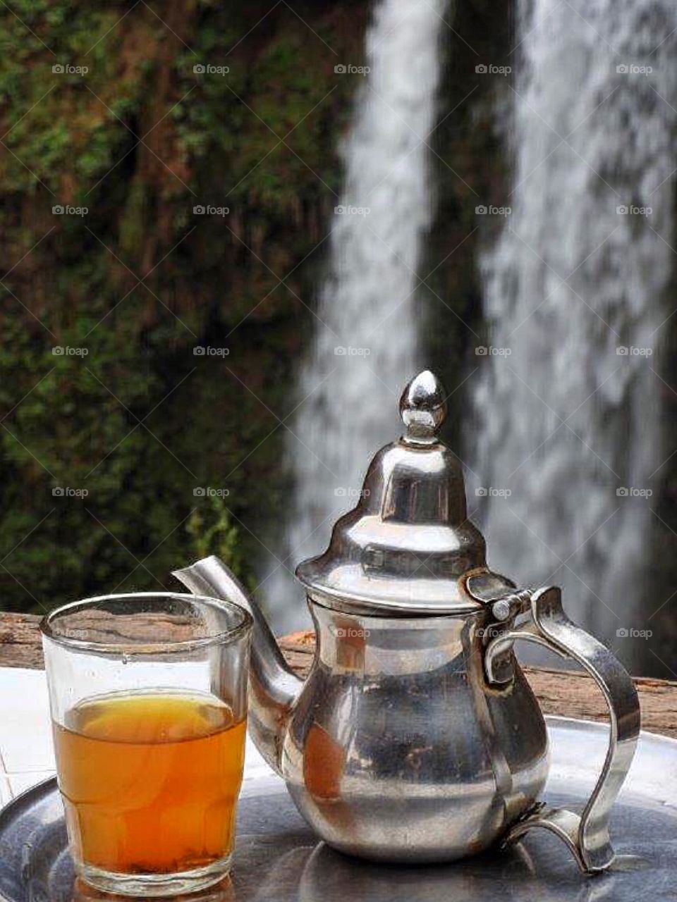 Close-up of tea cup near waterfall