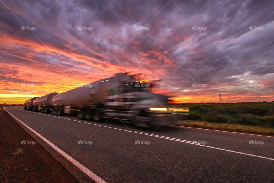 Road train truck showing movement with dramatic sunrise