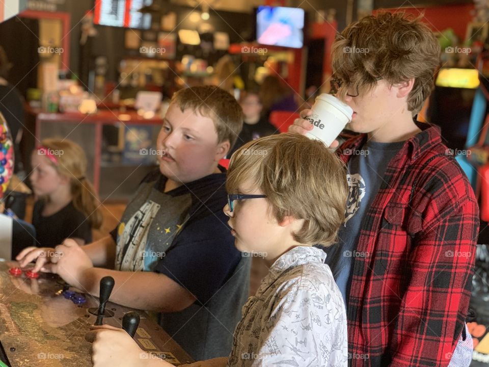 Hanging at the local arcade, enjoying the games from their parents generation. Future hipsters drinking coffee and hanging out.