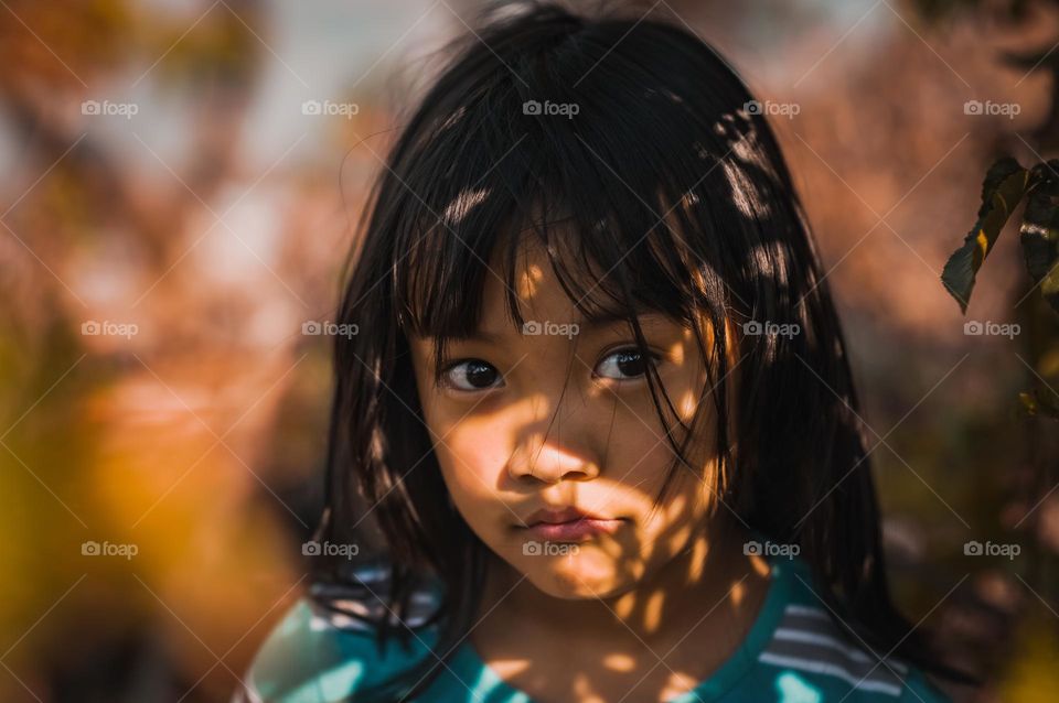 Portrait of a small girl in the shades of bushes.