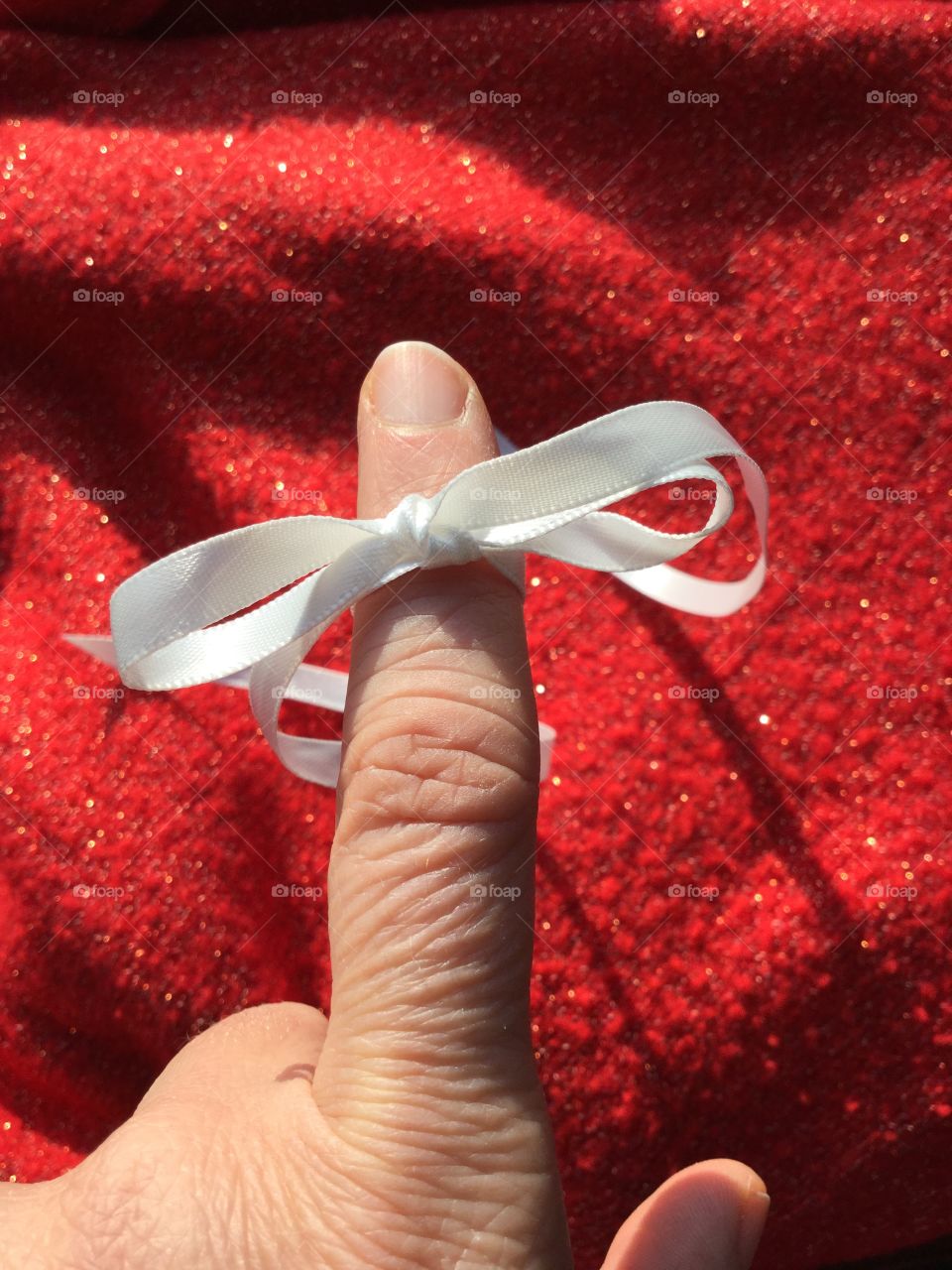 Tying the knot. Finger with white satin ribbon in a knot.