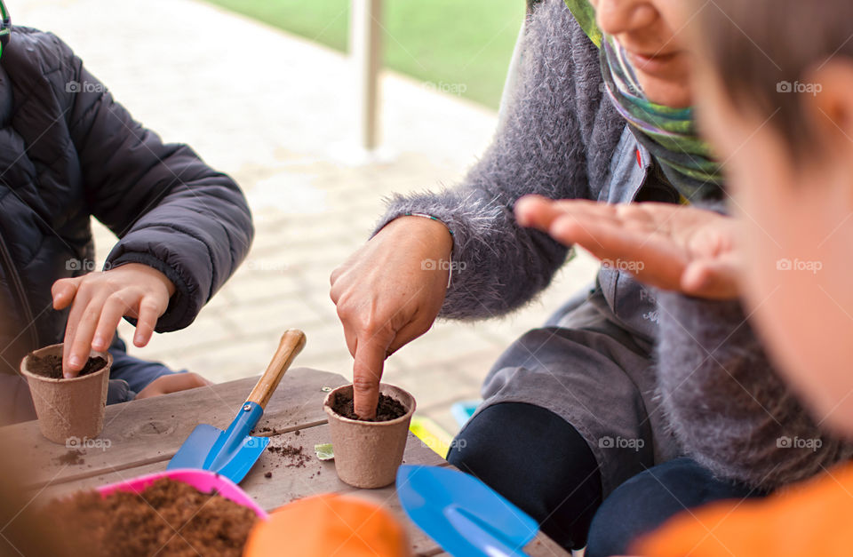 Children in the backyard learning how to plan seeds in garden. Family time.