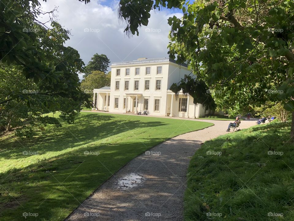 People can be seen here at a distance enjoying warm sunshine at the home of Agatha Christie the famous writer. Greenlands can be found in Devon, UK.