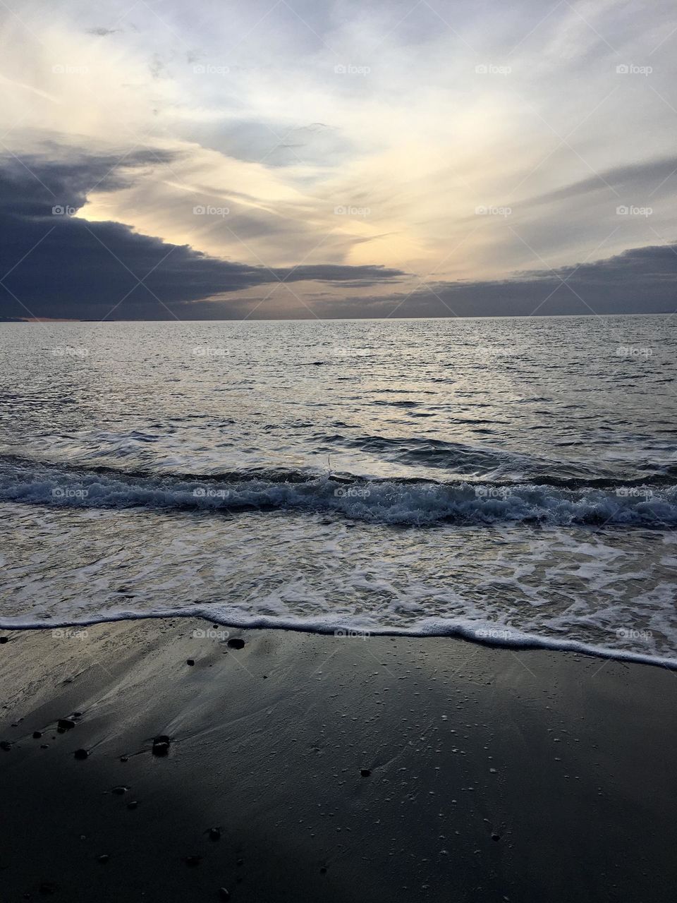 Cloudy sunset at beach with waves 