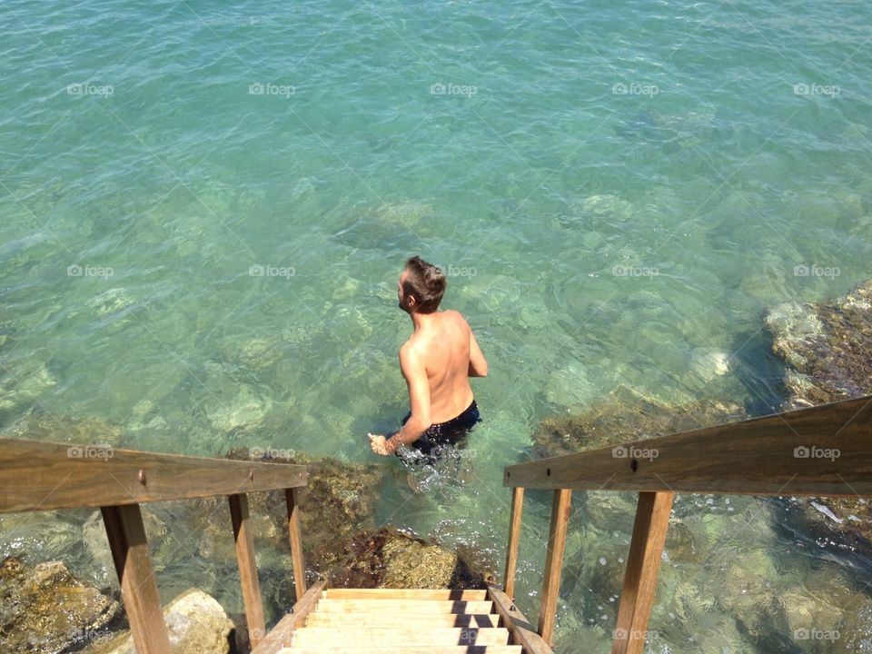 Man under the steps. Man ready to swim 