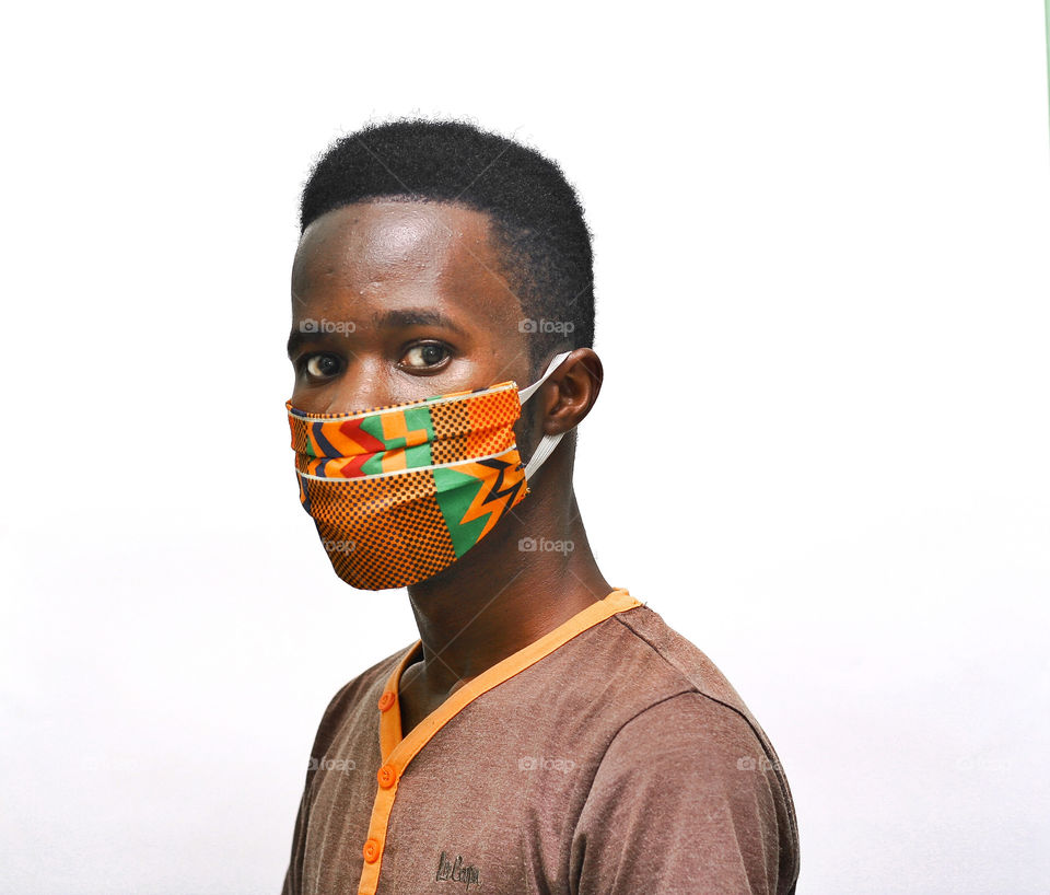 Wearing and an african design nose mask in a white isolated background staring at the camera
