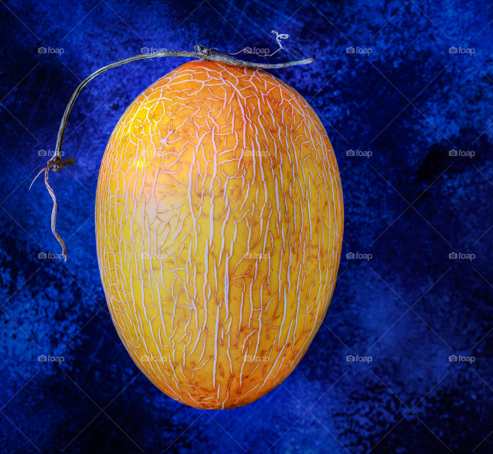Ripe orange honey melon on a contrasting textured blue background. Concept of natural seasonal fresh fruit and harvest. Food photos, top view, horizontal orientation