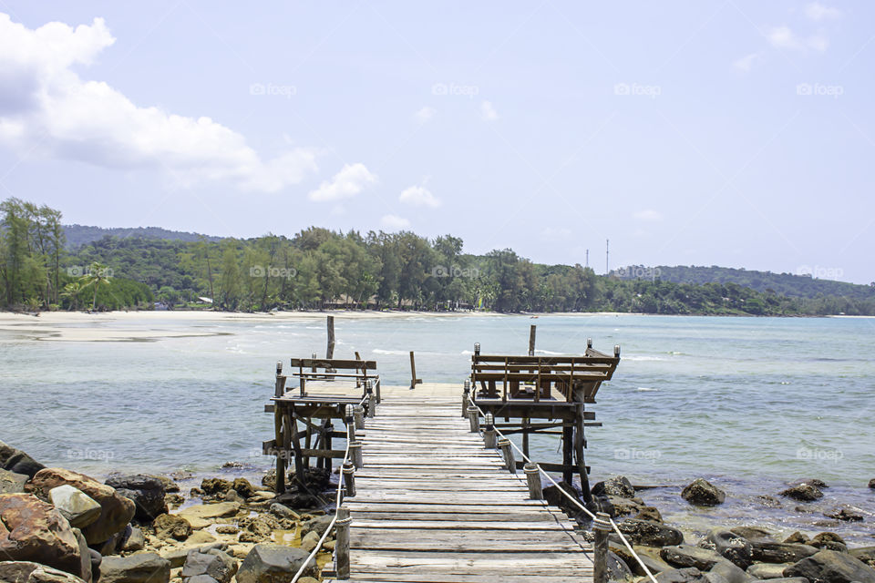 Wooden bridge pier boat in the sea and the bright sky at Koh Kood, Trat in Thailand.