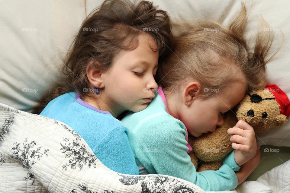 Siblings cuddling each other in bed