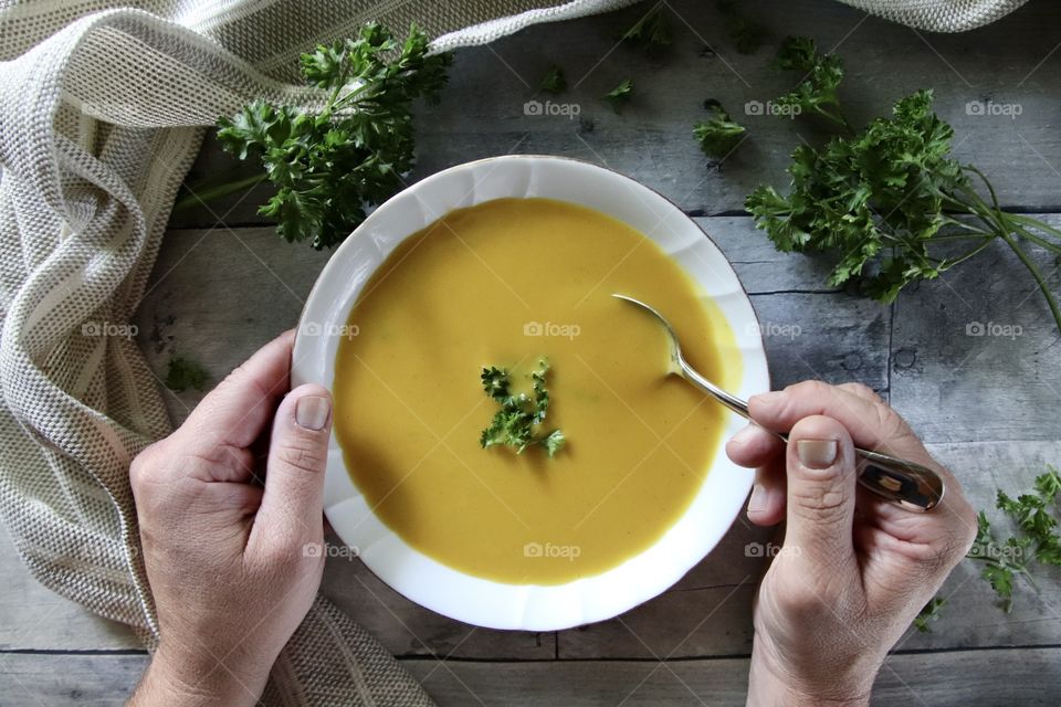 Man eating butternut squash soup with fresh parsley 