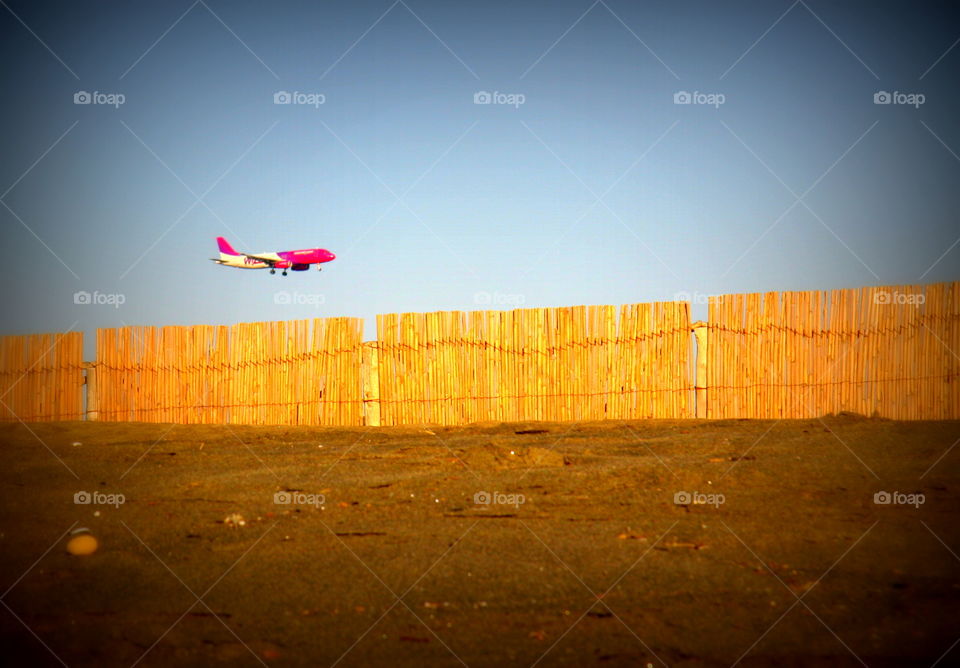 plane at low altitude landing near a beach with a fence