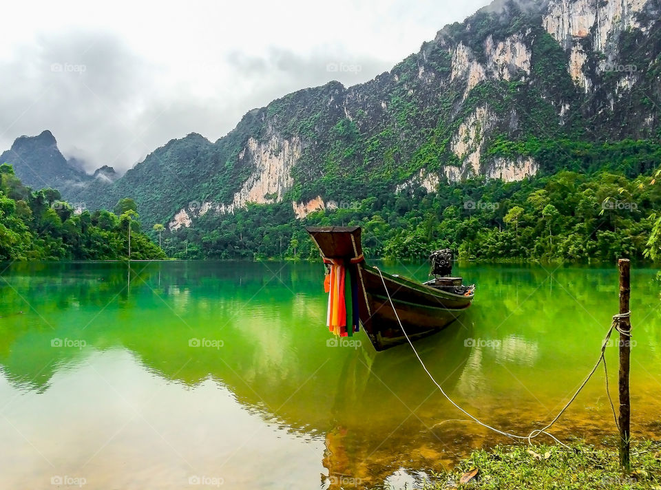 Lonely long-tailed boat in lake and mountains 