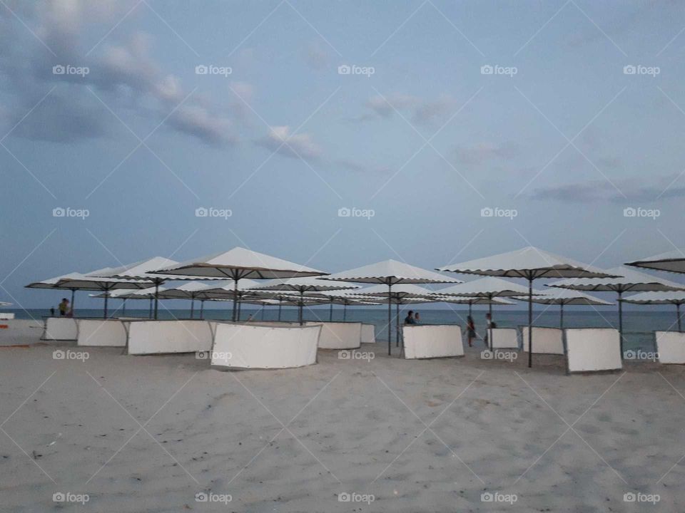 Evening at the beach with white umbrellas