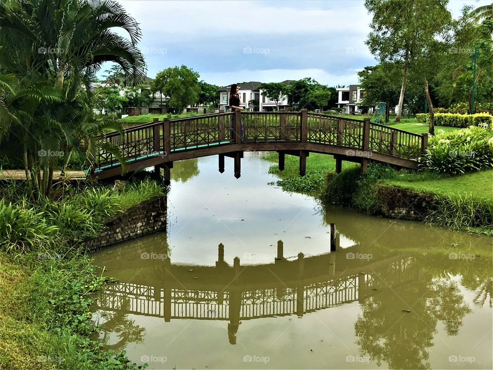 A  reflected image of a girl and bridge in the water
