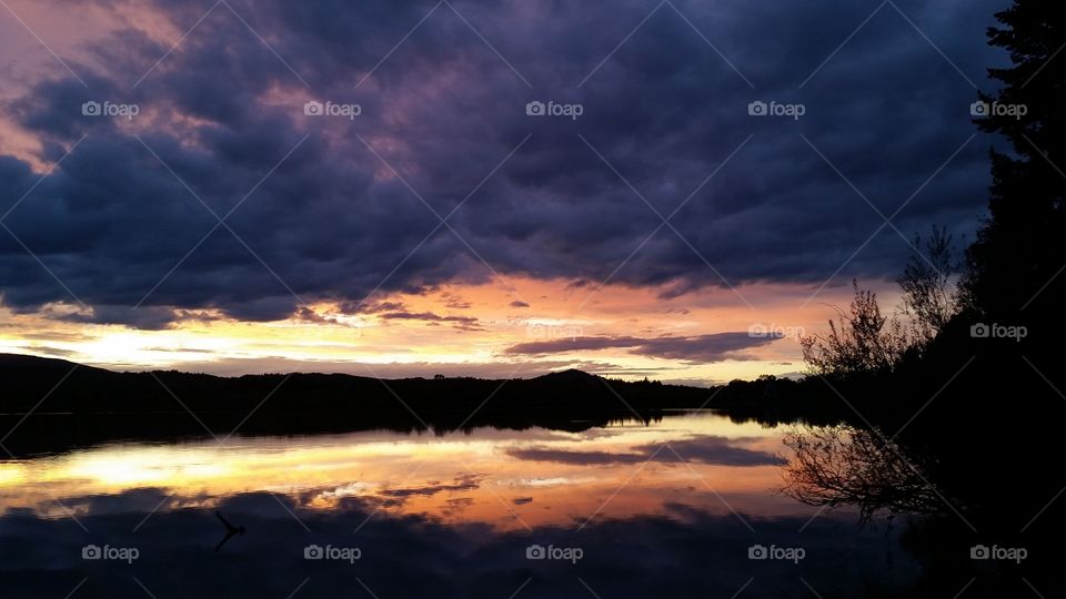 Sunset with dramatic clouds reflected in lake