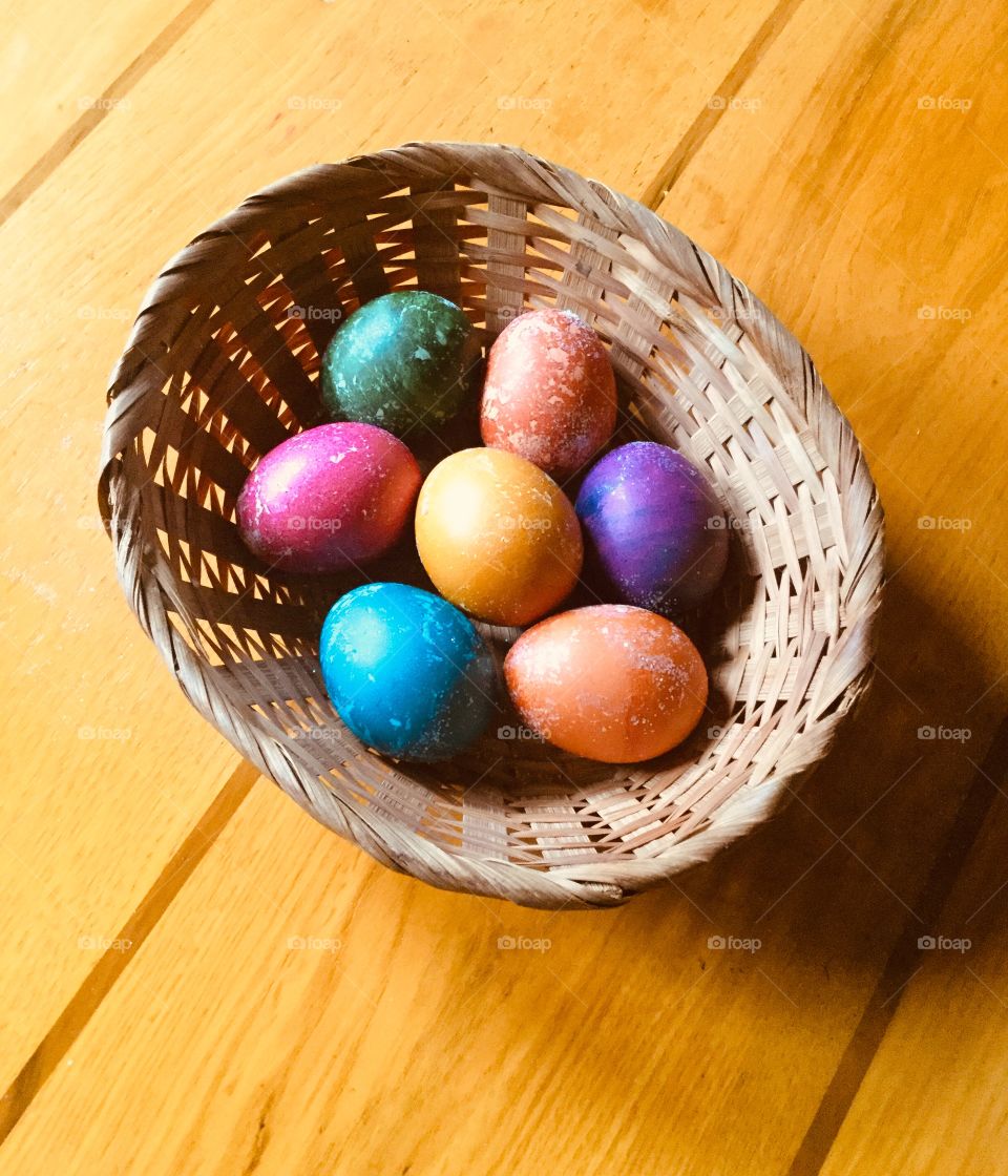 A rustic basket of brightly colored Easter eggs.