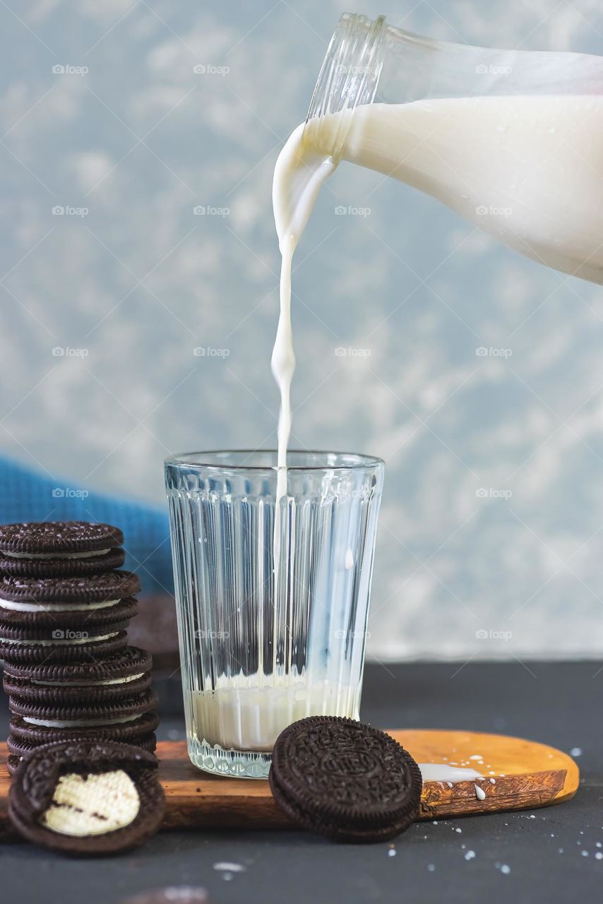 Milk pouring in glass with oreo biscuits.