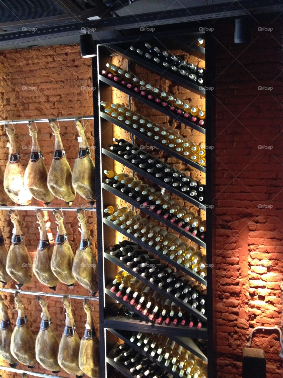 Spanish Jamón - Ham hanging on the wall and bottles of wine on the shelf in a restaurant in Barcelona, Spain