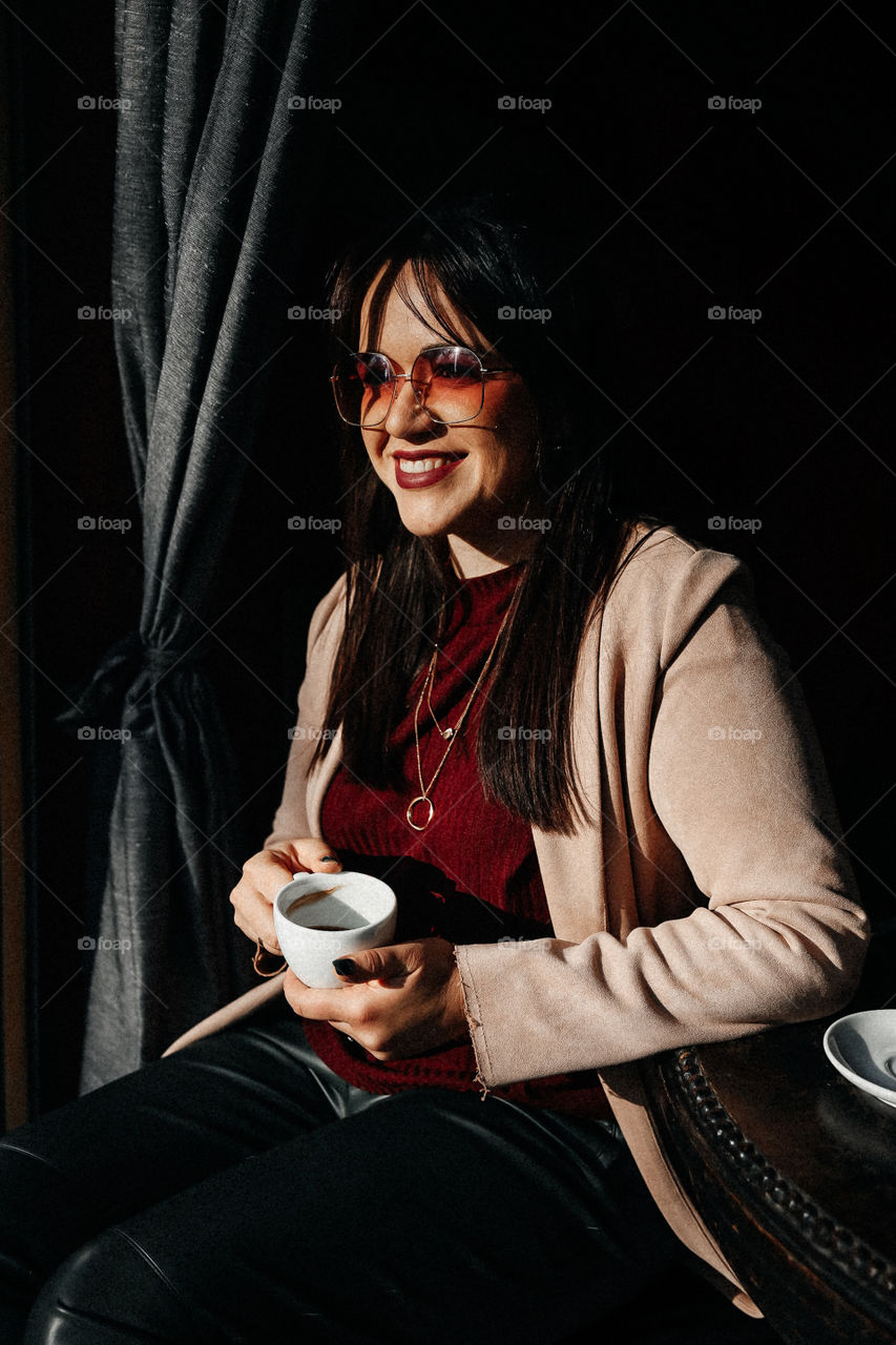 Beautiful brunette girl smile and take cup of coffee in street cafe