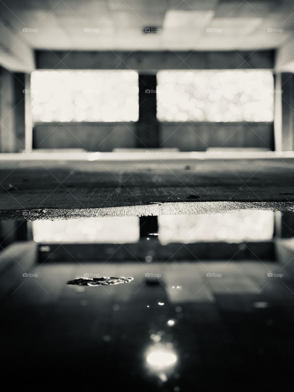 Concrete parking deck with puddle reflections in black and white. A desolate, eerie effect.
