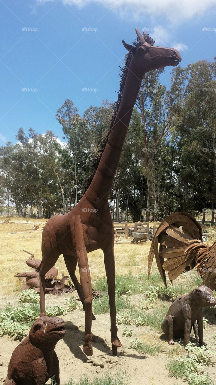 Copper Giraffe in the Desert Surrounded by Assorted Creatures