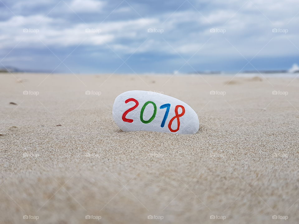 2018 year carved and painted on a stone with beach background