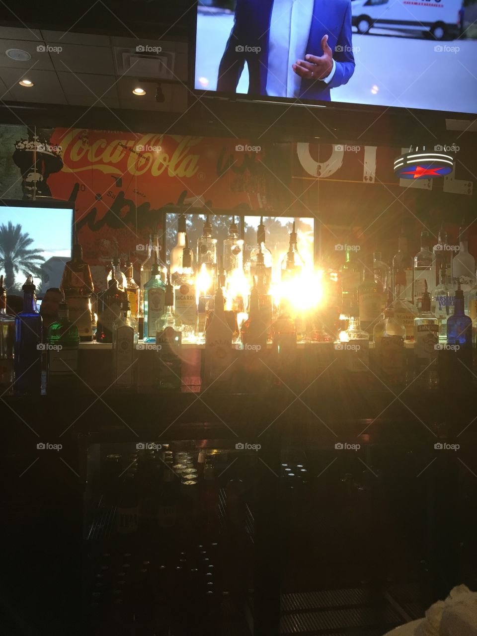 Sunshine shining through liquor bottles at the bar