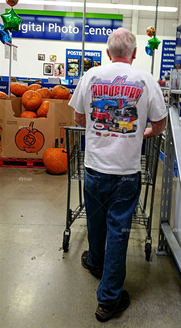 Senior pushing shopping cart at warehouse store.