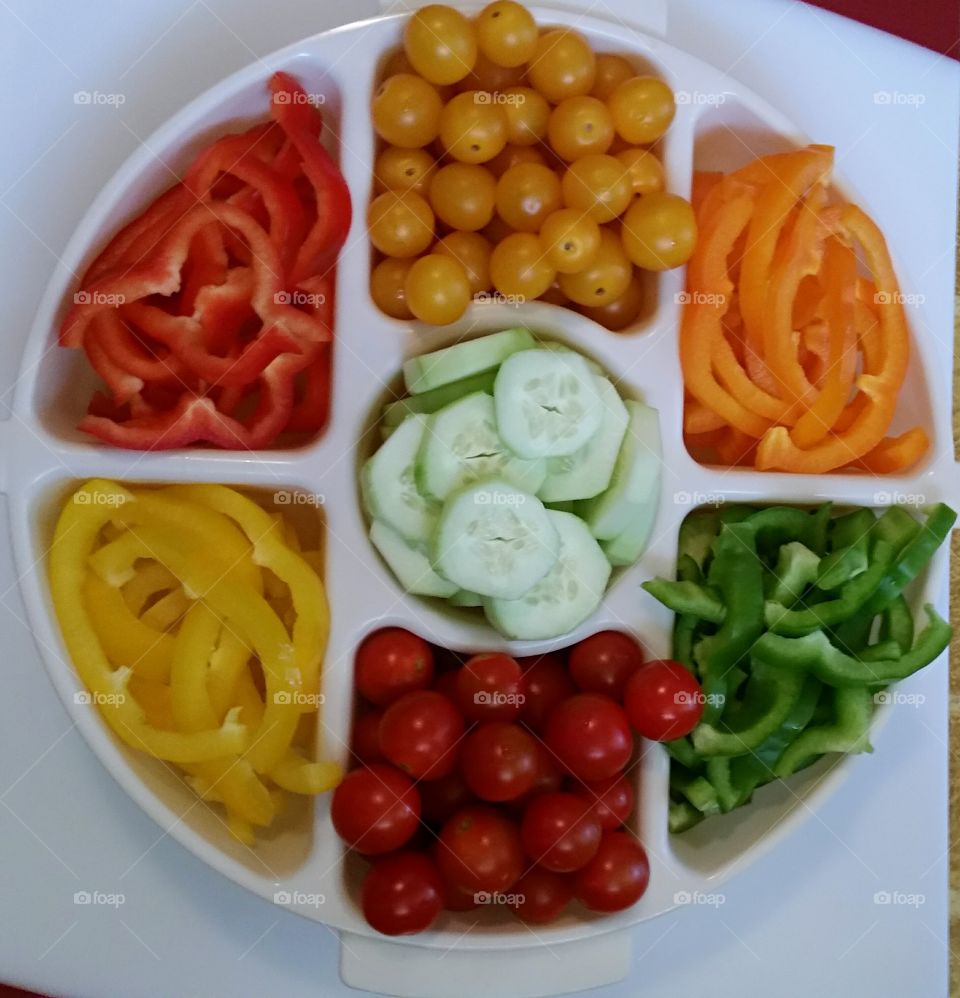 Platter filled with assorted slices of colorful  fresh vegetables.